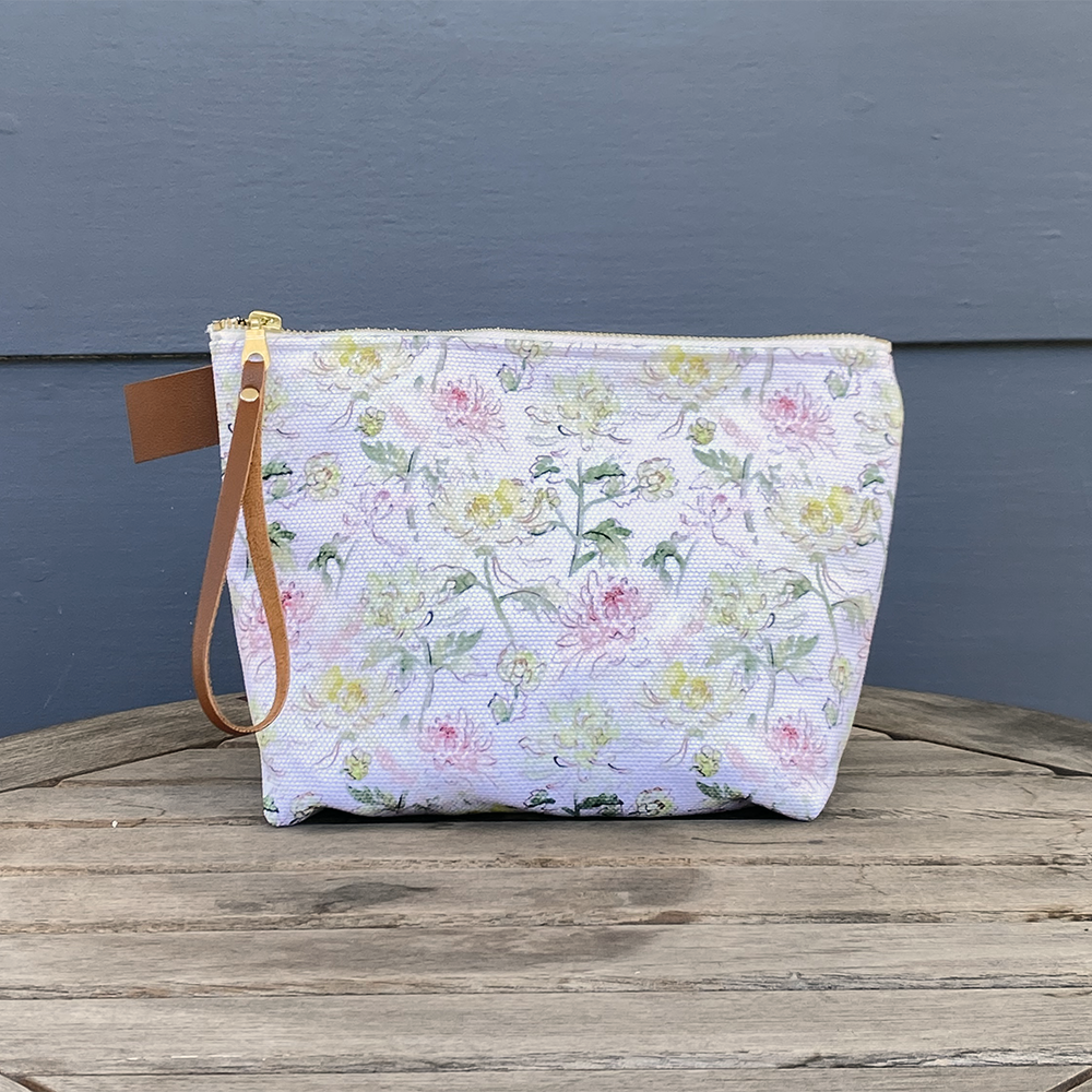 Large Carry All Make Up Bag with denim lining. Chrysanthemum floral pattern. Shown on table.
