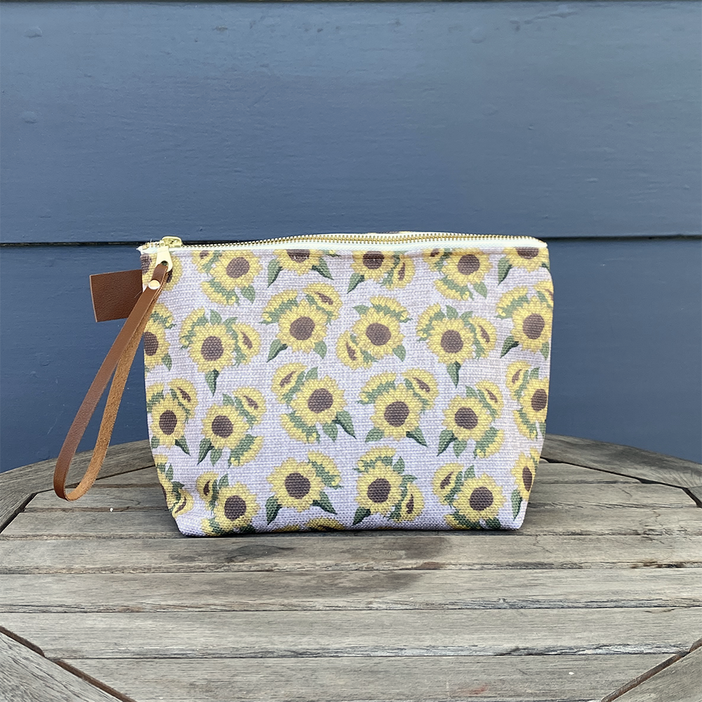 Large Carry All Make Up Bag with denim lining. Sunflower floral pattern. Shown on table.