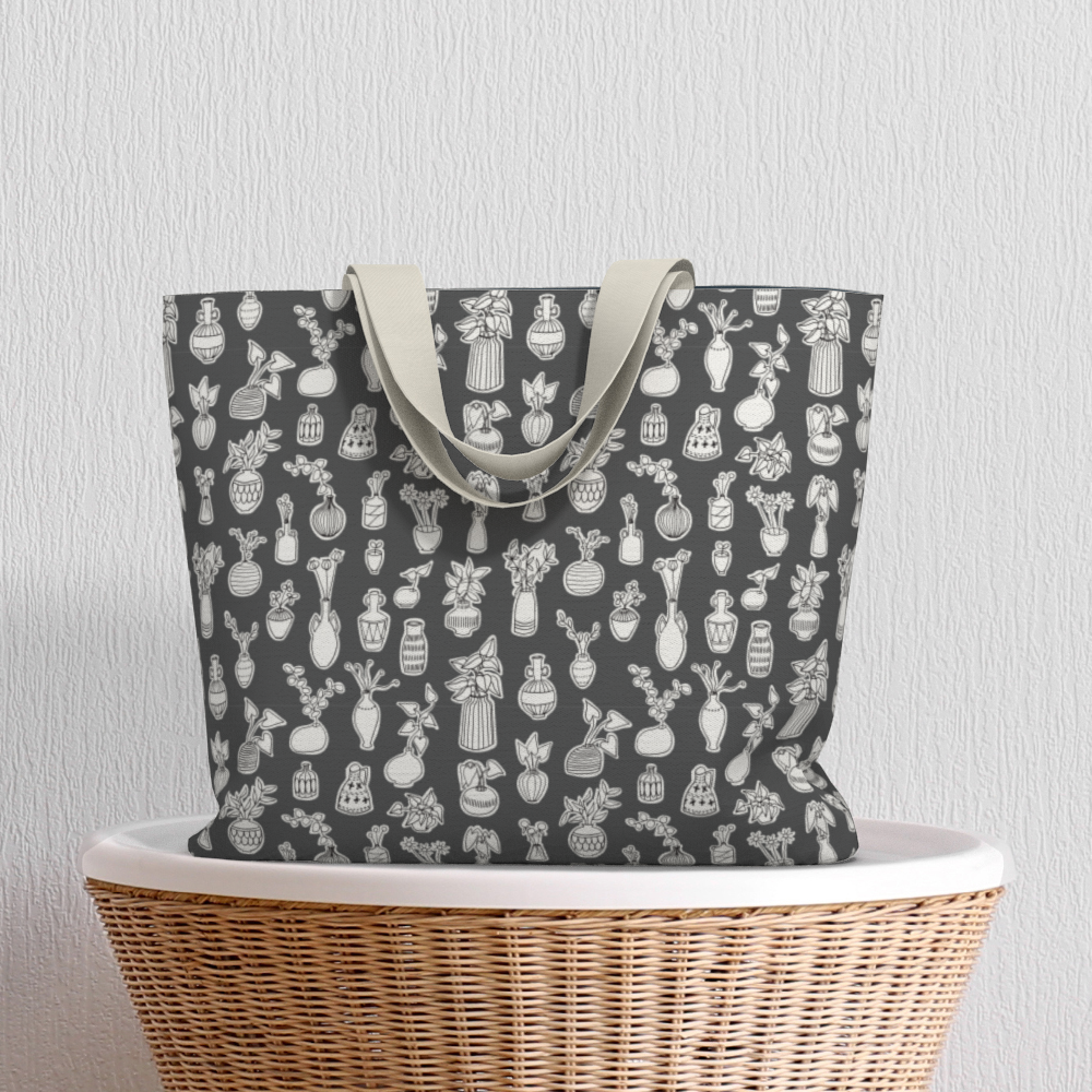Oversized Fully Lined Cotton Tote Bag with sturdy 1 ½ inch strap. Whimsical gray pattern featuring doodles of house plants. Shown on wicker basket.
