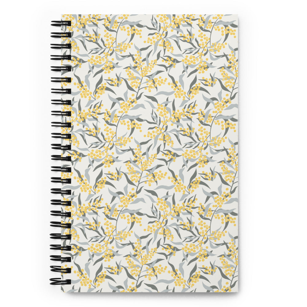 Bullet journal spiral notebook with mimosa branch pattern, light background. Front cover.
